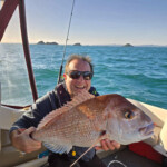 Smiling angler holding a large snapper on a boat with K-Labs custom fishing rod in background